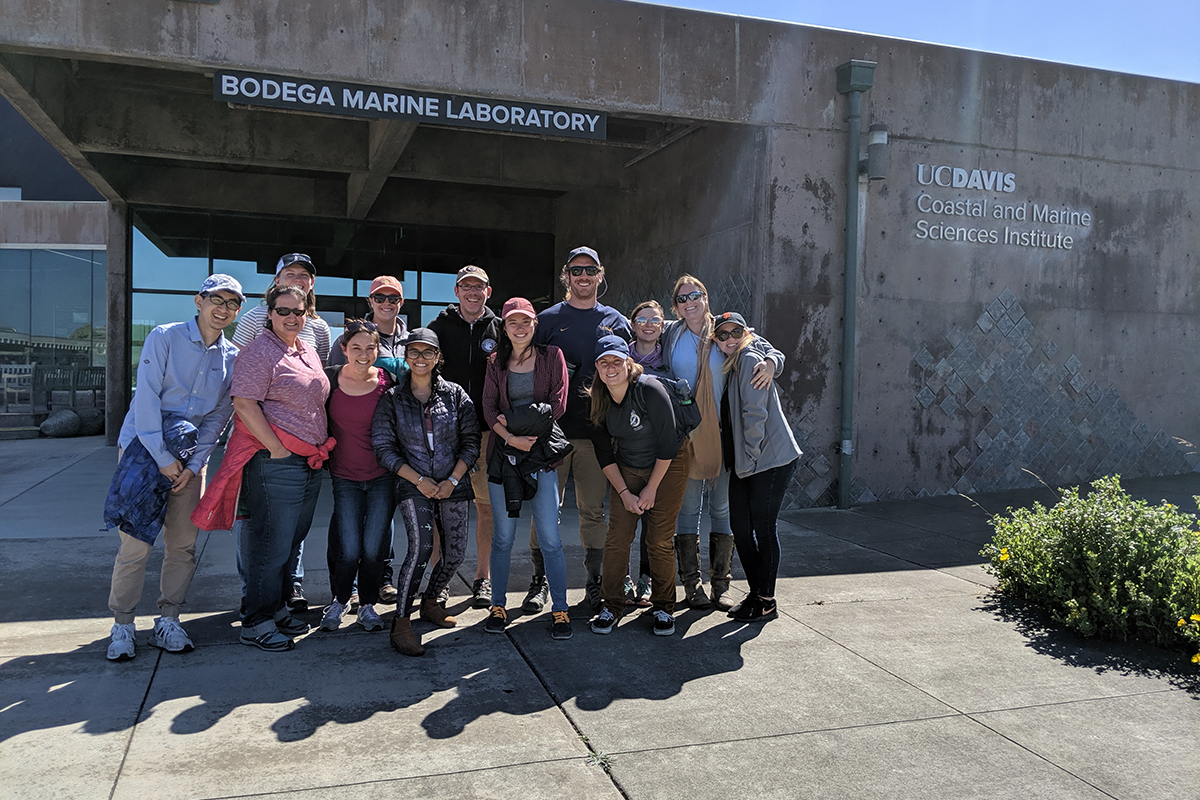 A group of students standing outside of a building with cement walls and a glass front, the sign reads "Bodega Marine Laboratory"