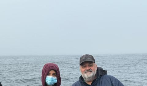 SRJC intern Esme Padilla-Garcia standing with another fisher on a boat, holding a fish caught as part of the CCFRP program