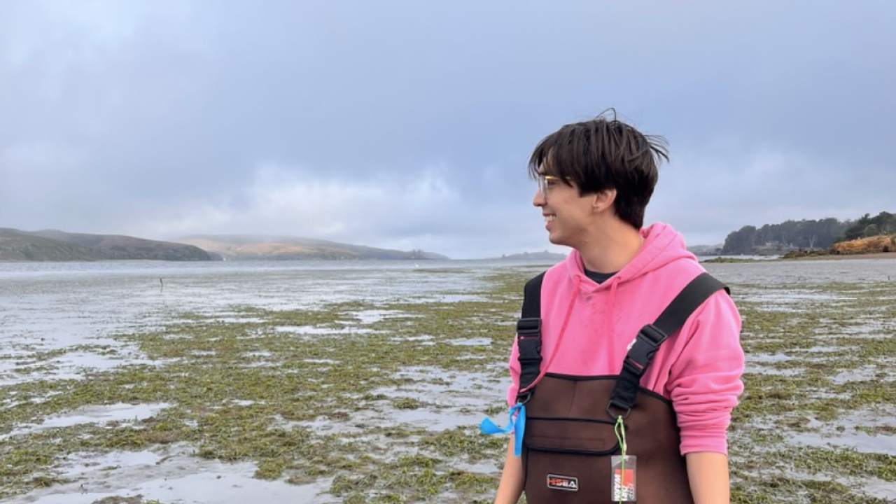 Lucas Hernandez wearing waders and walking in a mudflat
