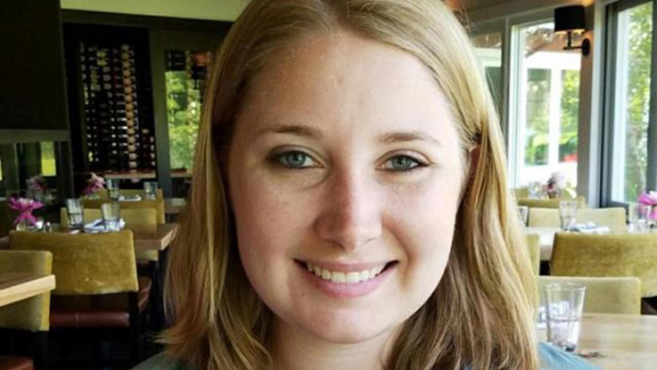 A portrait of a person with shoulder length reddish blond hair smiling at the camera
