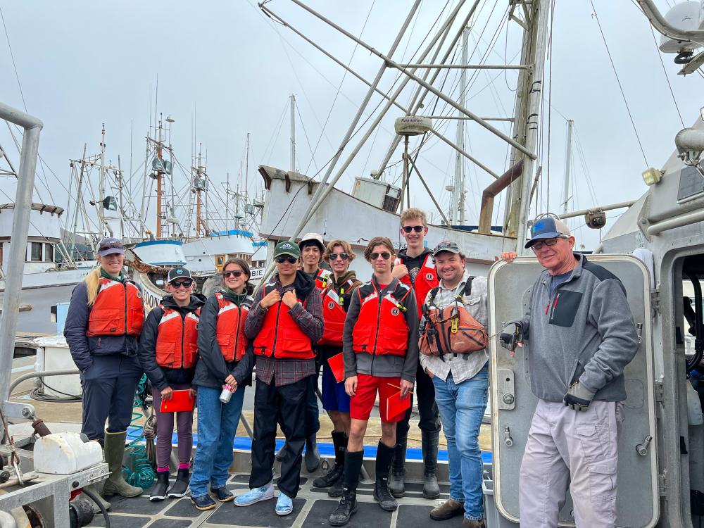 A group of students gathered on deck of a boat, wearing brightly colored life vests
