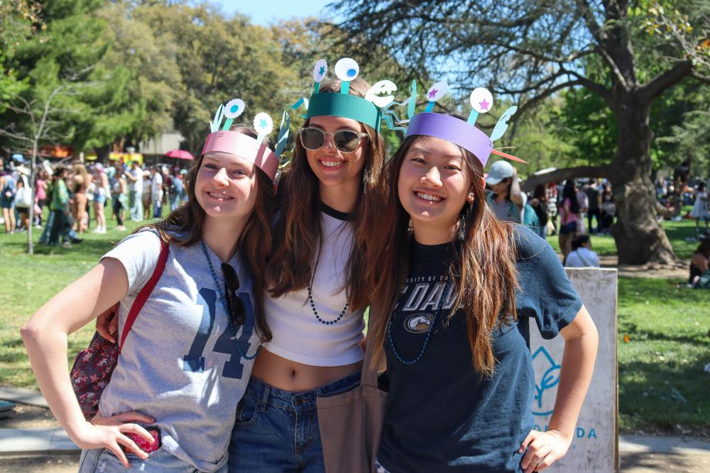 Three UC Davis students posing together with paper crab hats on at Picnic Day