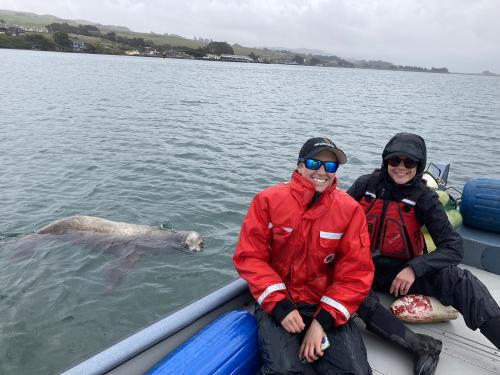 Two people in a boat with a sea lion beside it