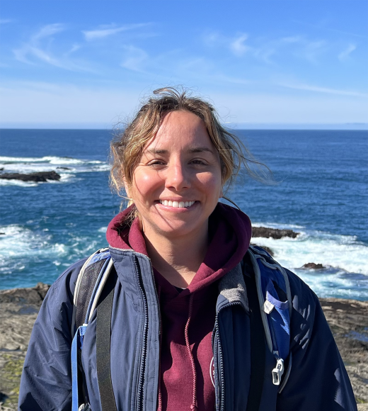 A person standing in front of the ocean and smiling at the camera