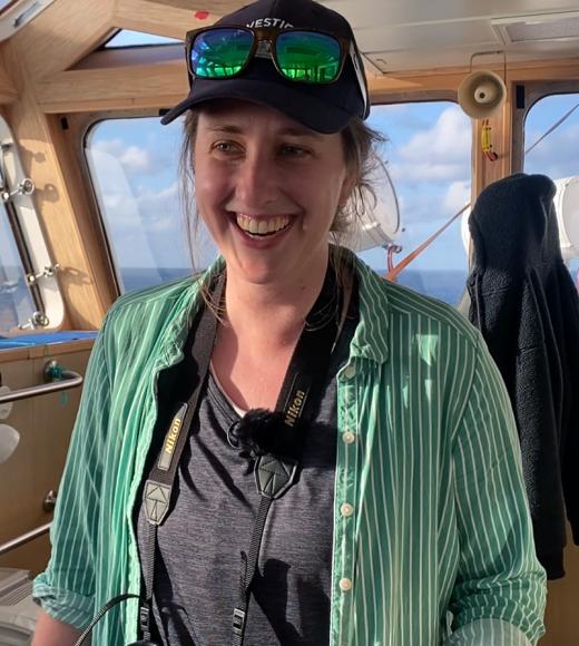 A photo of Jessica Bolin standing inside a boat that is out on the water.
