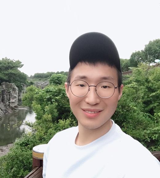 A profile image of a person wearing a baseball hat and white t-shirt, standing in front of an outdoor scene with trees in the background.