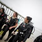 A group of people in scuba gear standing on a sandy beach.