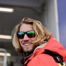 A portrait of Jefferson Humbert wearing a bright orange jacket and sunglasses