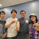 A group of people holding up small marine creatures called chitons