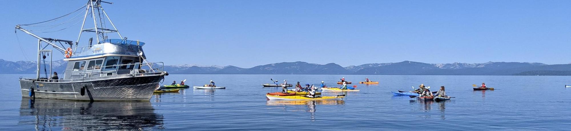 A group of kayaks in the water next to a larger boat